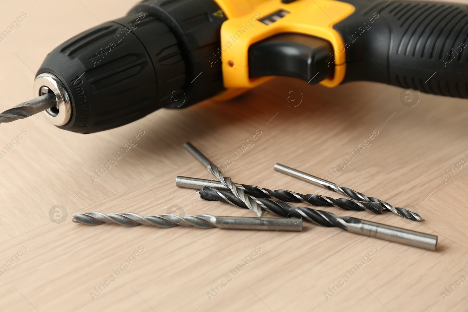 Photo of Cordless electric drill and bits on wooden surface