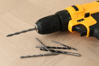 Cordless electric drill and bits on wooden surface