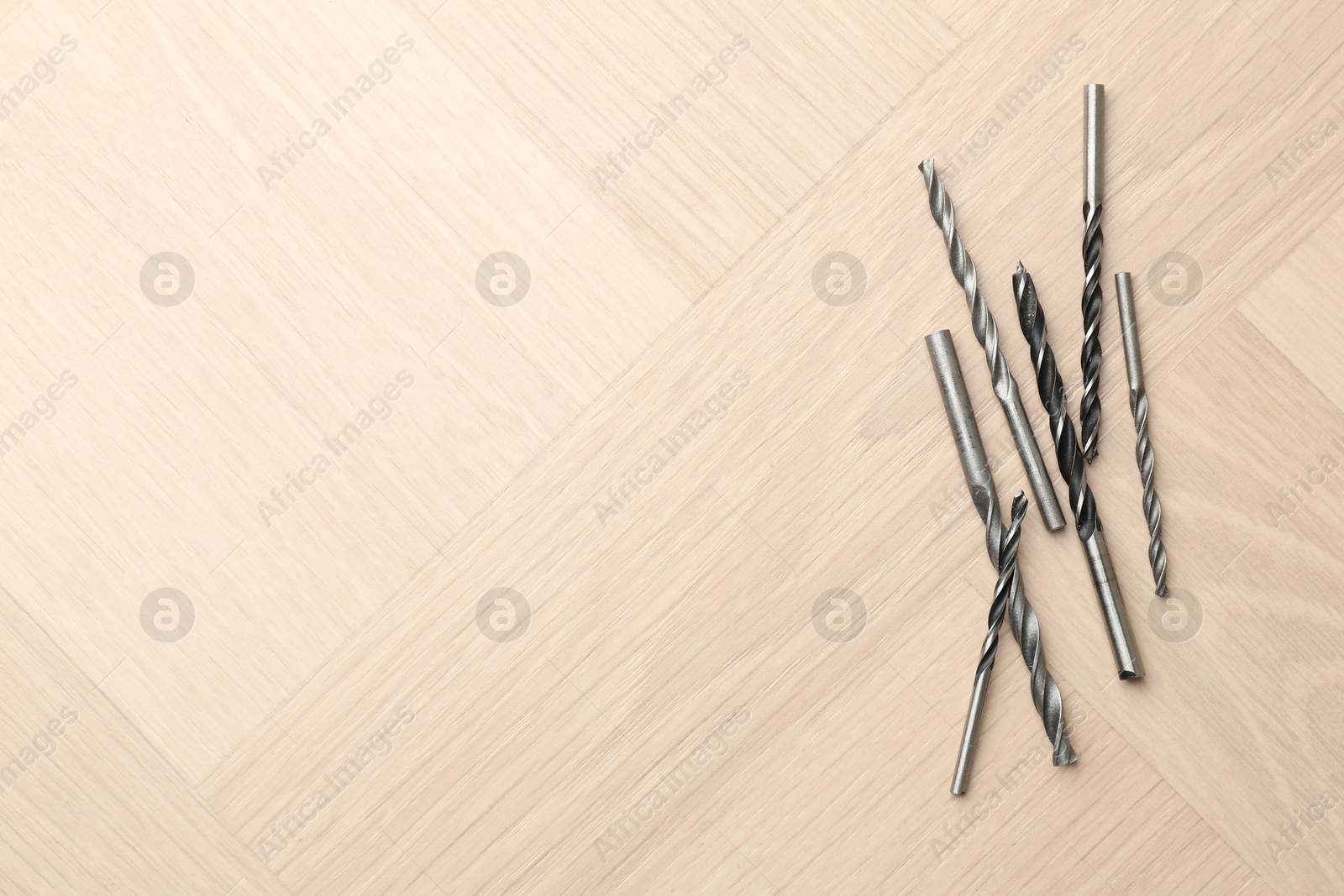 Photo of Many different drill bits on wooden surface, top view. Space for text