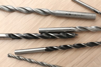 Photo of Many different drill bits on wooden surface, top view