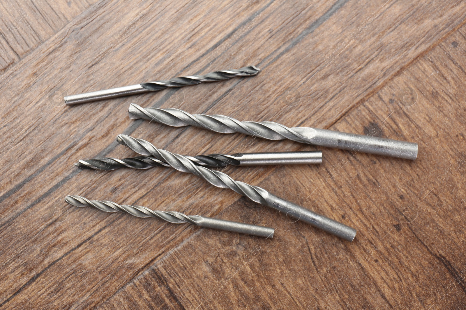 Photo of Many different drill bits on wooden surface, top view