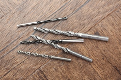 Photo of Many different drill bits on wooden surface, top view