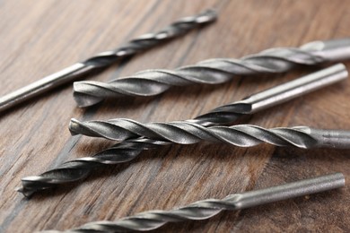 Many different drill bits on wooden surface