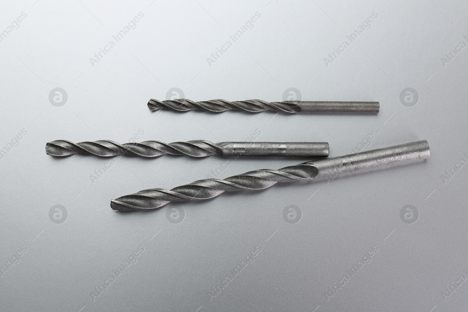 Photo of Different drill bits on light grey background