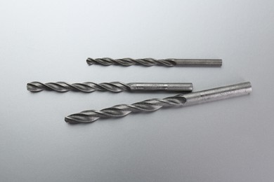 Photo of Different drill bits on light grey background