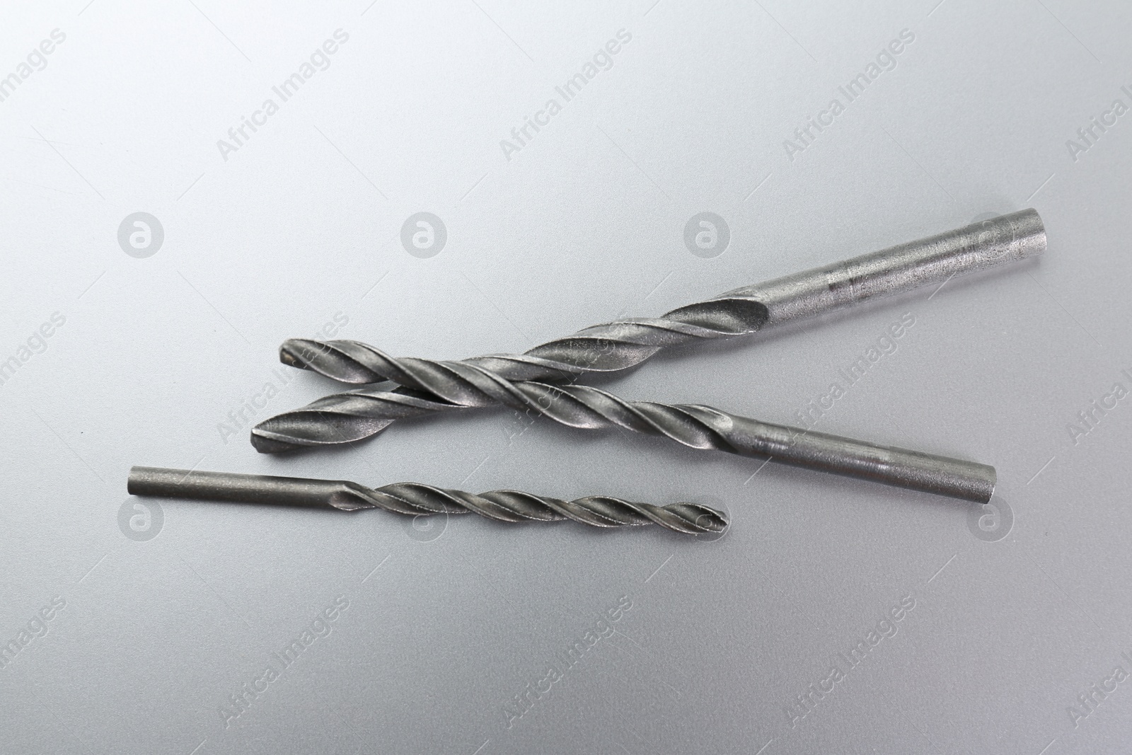 Photo of Different drill bits on light grey background, top view