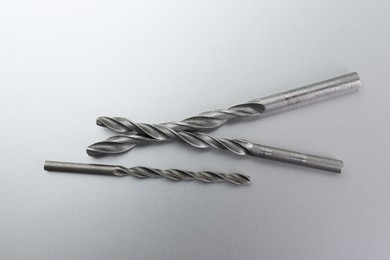 Different drill bits on light grey background, top view