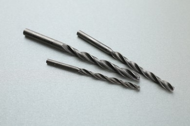 Photo of Different drill bits on light grey background, above view