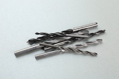 Photo of Many different drill bits on light grey background, above view