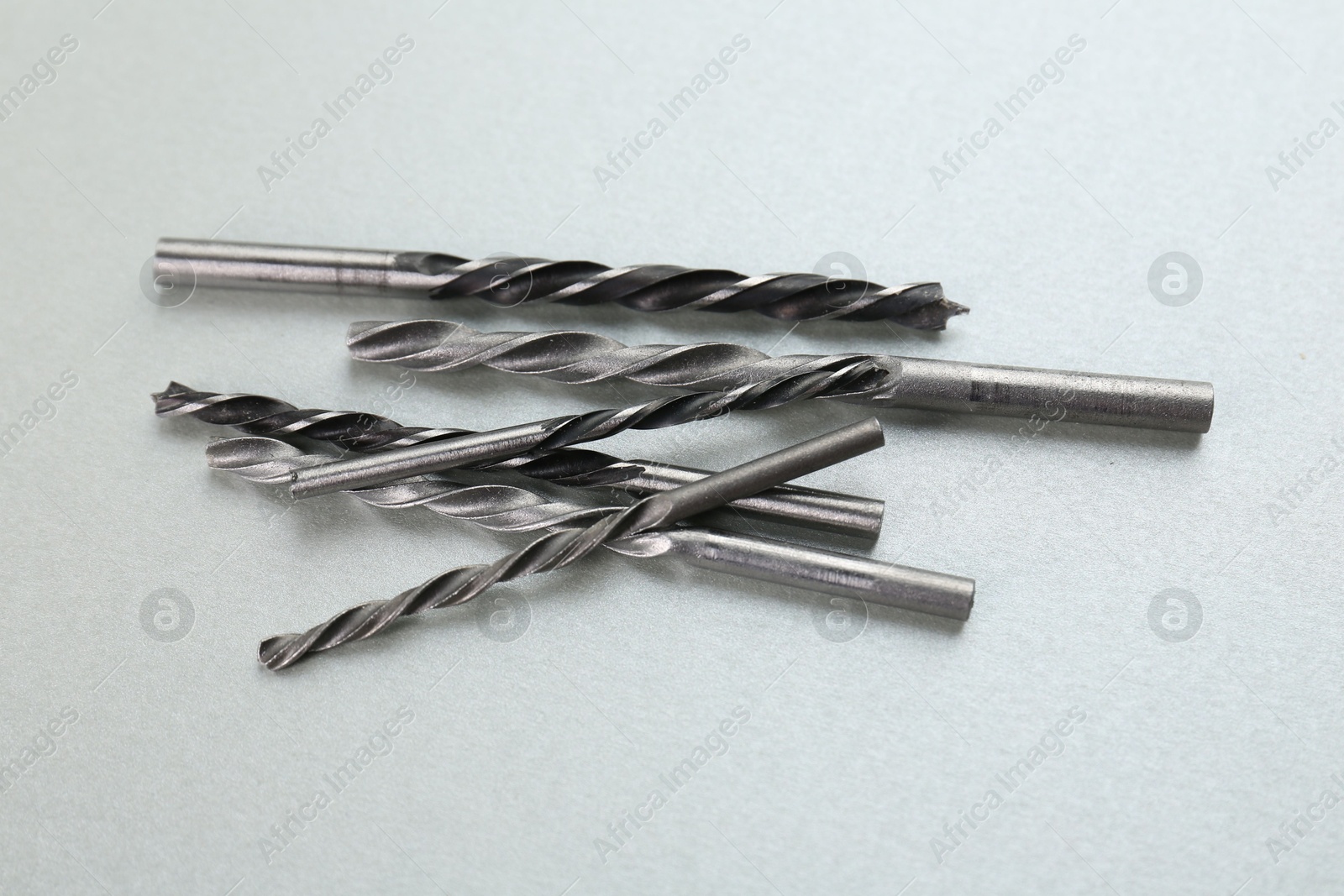 Photo of Many different drill bits on light grey background, above view