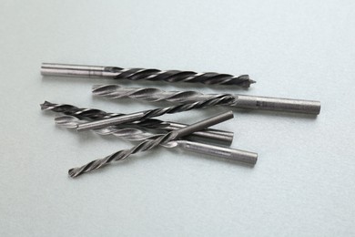 Many different drill bits on light grey background, above view