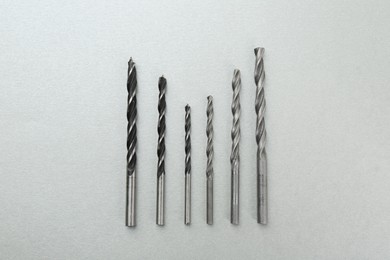 Many different drill bits on light grey background, top view