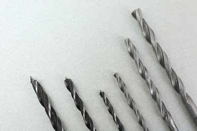 Photo of Many different drill bits on light grey background, top view