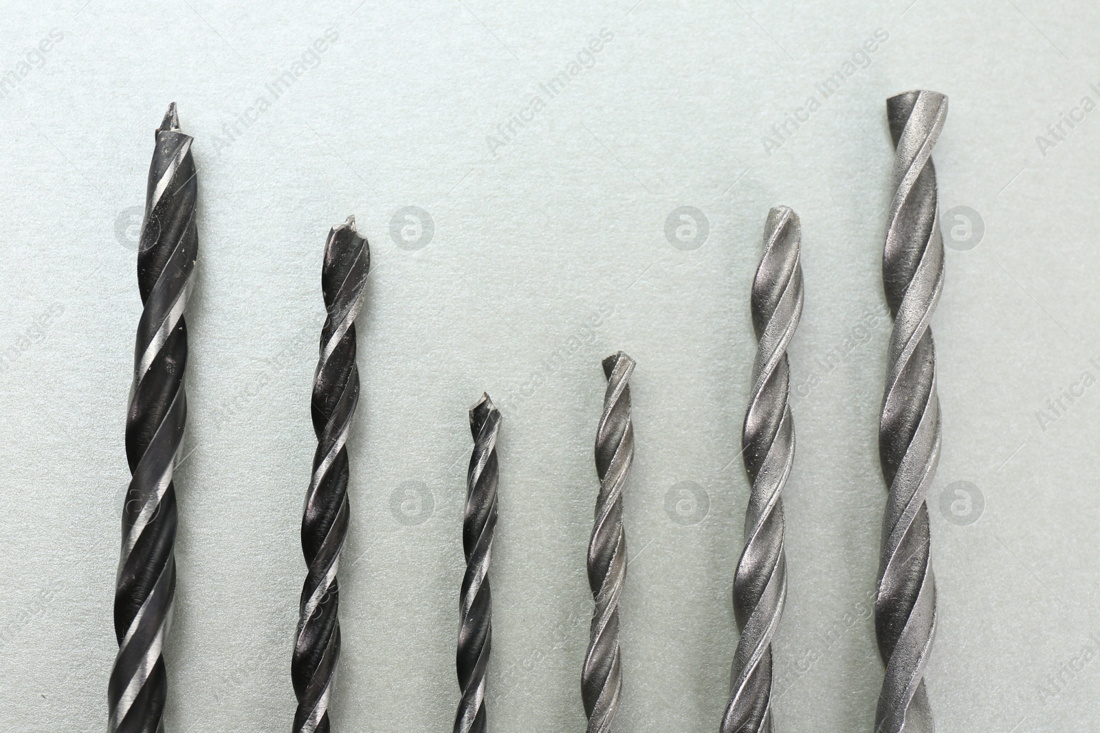 Photo of Many different drill bits on light grey background, top view