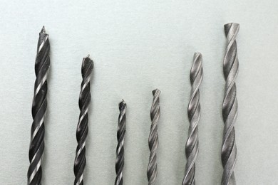 Many different drill bits on light grey background, top view