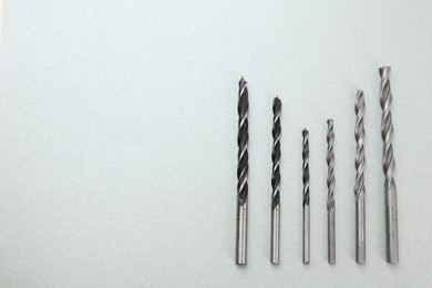 Many different drill bits on light grey background, top view. Space for text