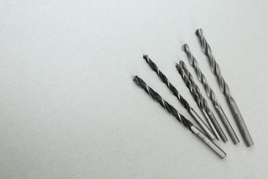 Many different drill bits on light grey background, top view. Space for text