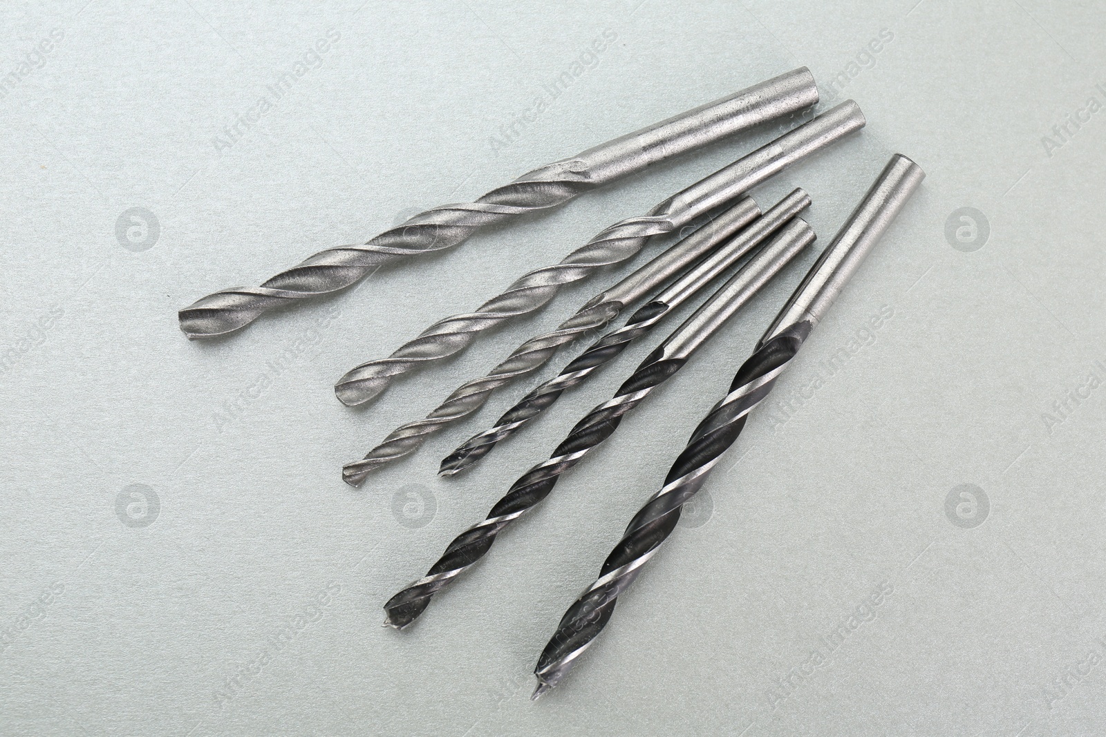 Photo of Many different drill bits on light grey background, top view