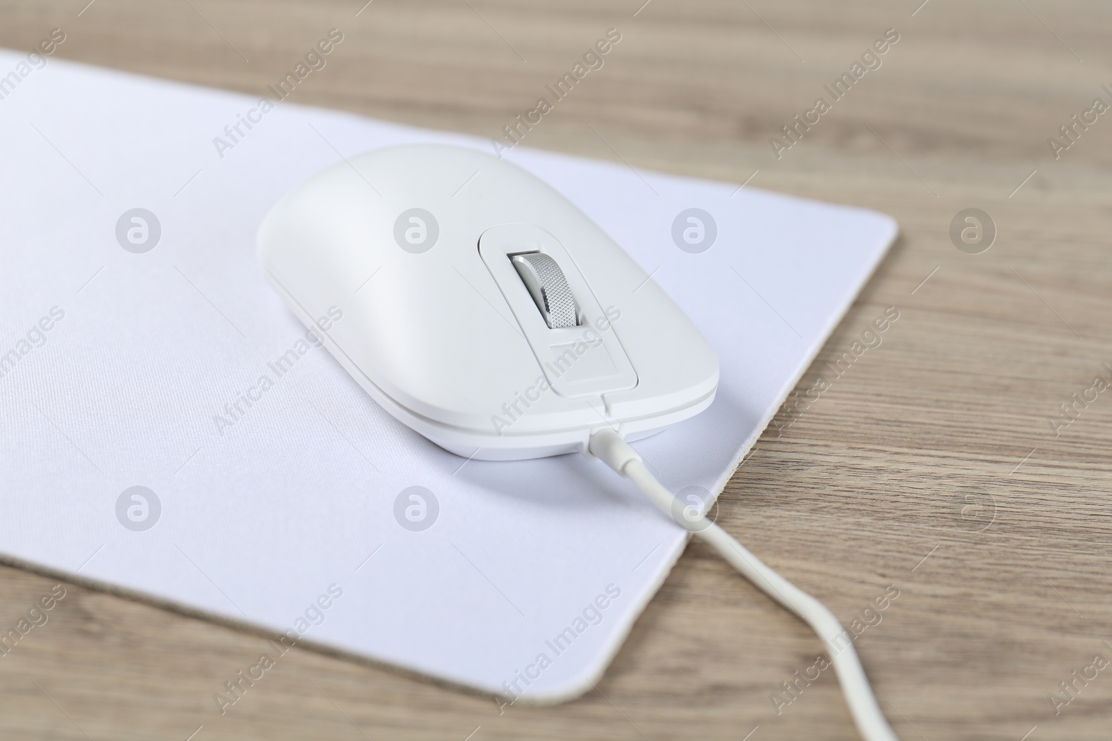 Photo of White computer mouse and mousepad on wooden table