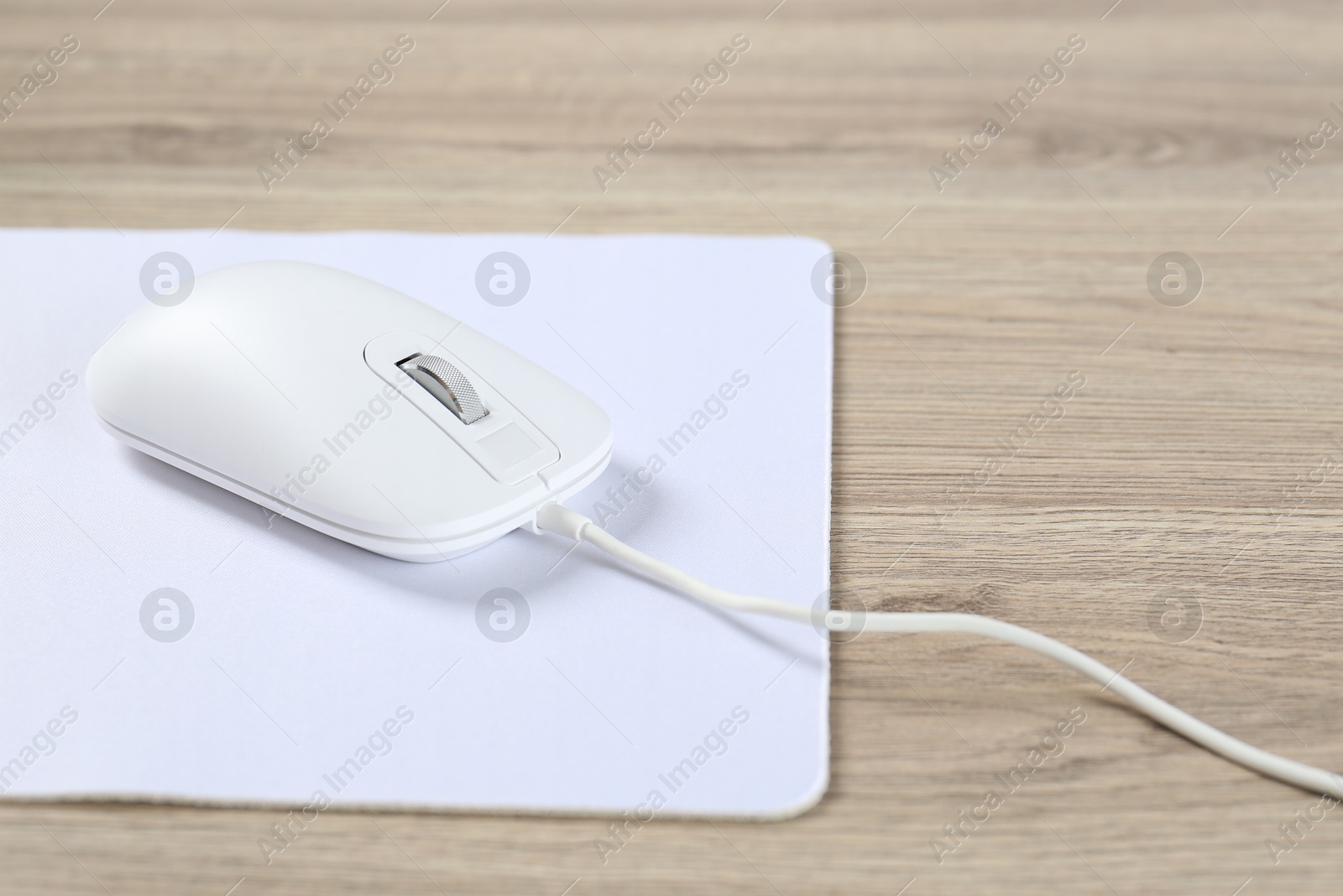 Photo of White computer mouse and mousepad on wooden table