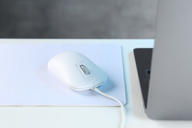 Photo of Computer mouse with mousepad and laptop on white table