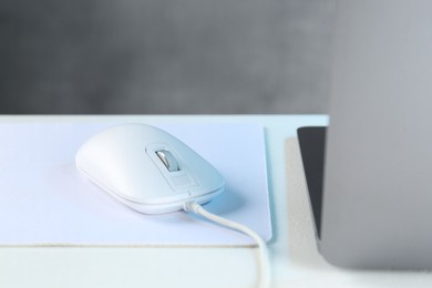 Photo of Computer mouse with mousepad and laptop on white table