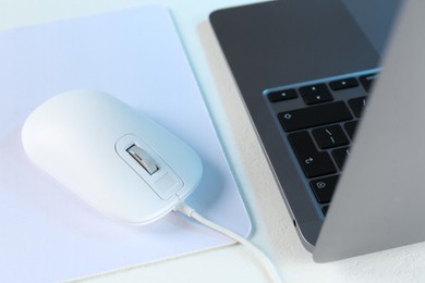 Photo of Computer mouse with mousepad and laptop on white table