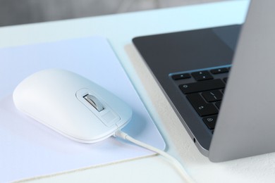 Photo of Computer mouse with mousepad and laptop on white table