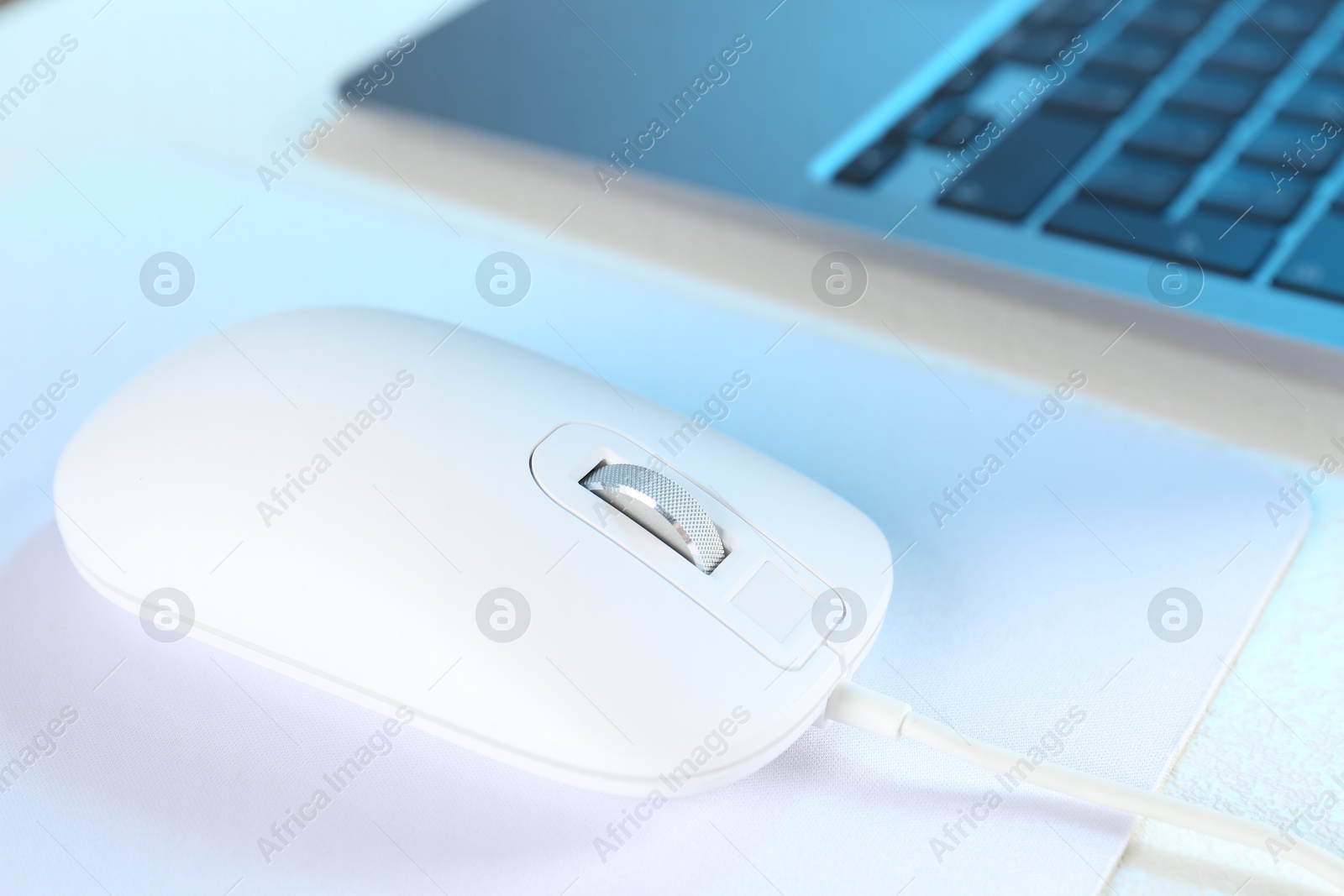 Photo of Computer mouse with mousepad and laptop on white table, closeup