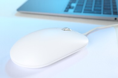 Photo of Computer mouse with mousepad and laptop on white table, closeup