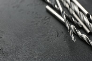 Photo of Many different drill bits on grey table, closeup. Space for text