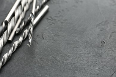 Photo of Many different drill bits on grey table, closeup. Space for text