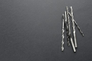 Photo of Many different drill bits on grey table, top view. Space for text