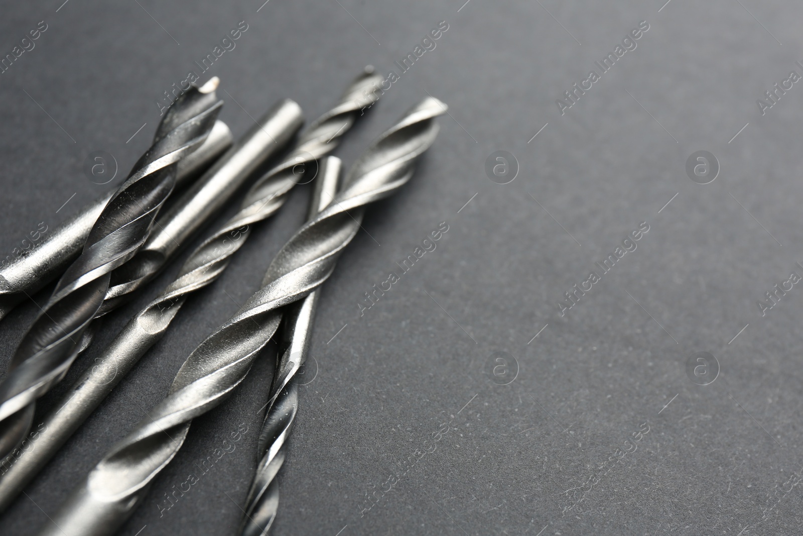 Photo of Many different drill bits on grey table, closeup. Space for text