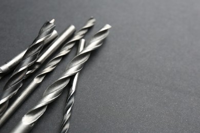 Photo of Many different drill bits on grey table, closeup. Space for text