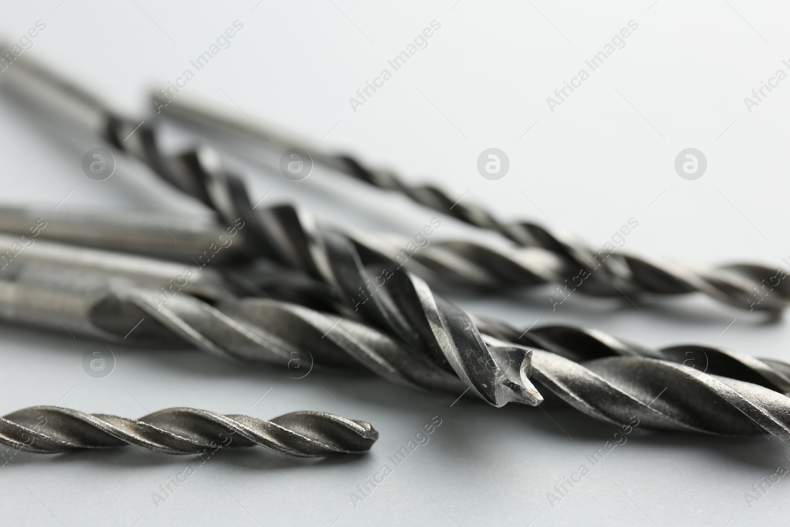 Photo of Many different drill bits on light grey background, closeup