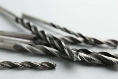 Photo of Many different drill bits on light grey background, closeup