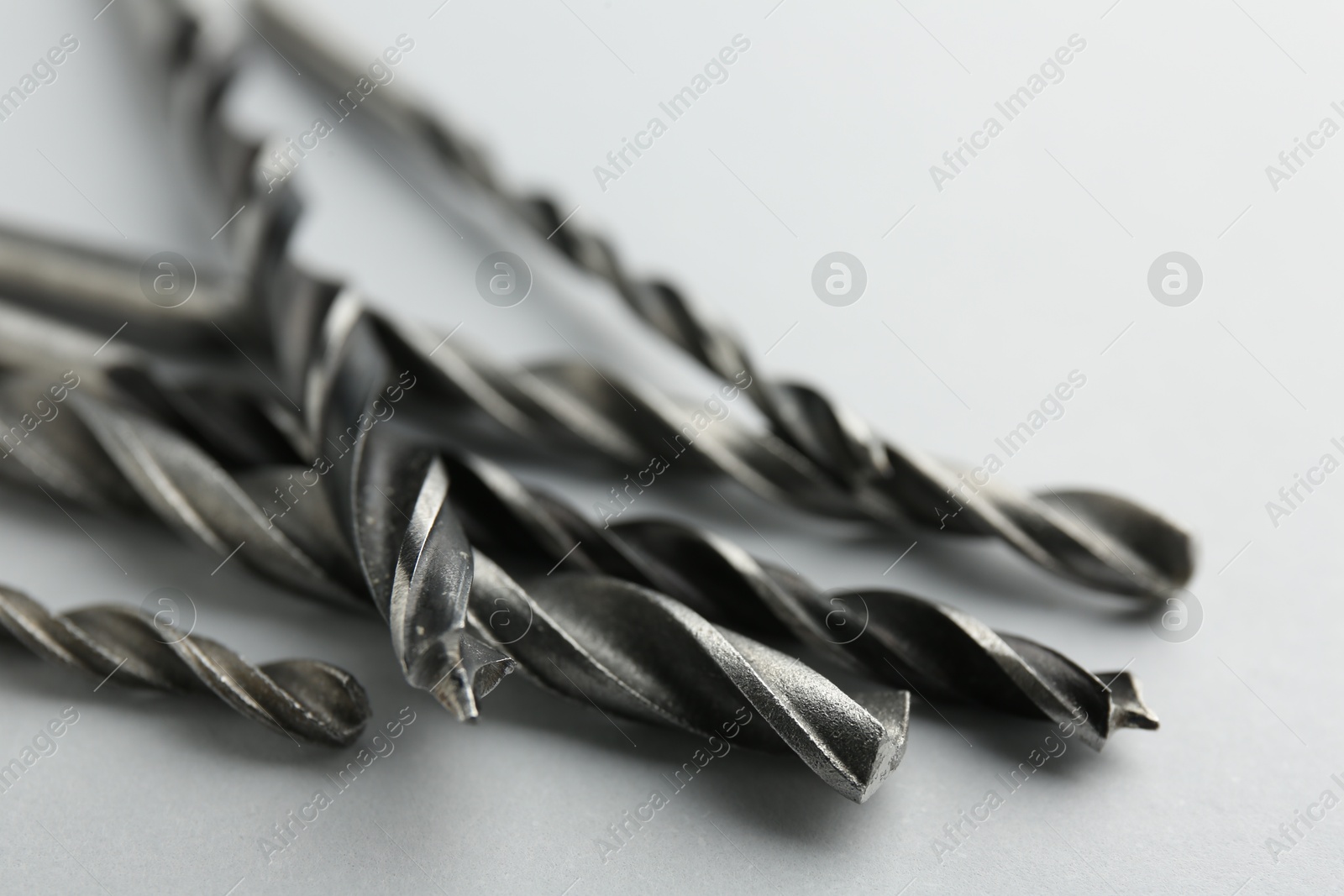 Photo of Many different drill bits on light grey background, closeup