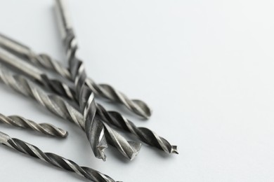 Photo of Many different drill bits on light grey background, closeup. Space for text