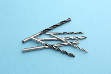 Photo of Many different drill bits on light blue background, top view