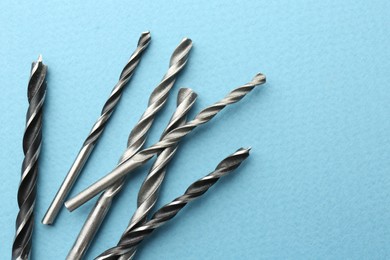 Many different drill bits on light blue background, top view. Space for text