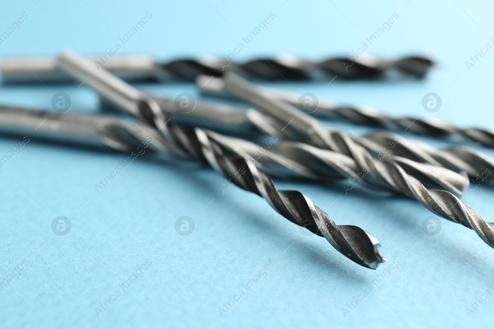 Photo of Many different drill bits on light blue background, closeup