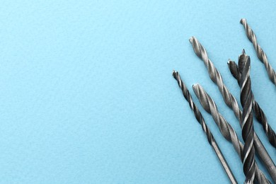 Many different drill bits on light blue background, top view. Space for text