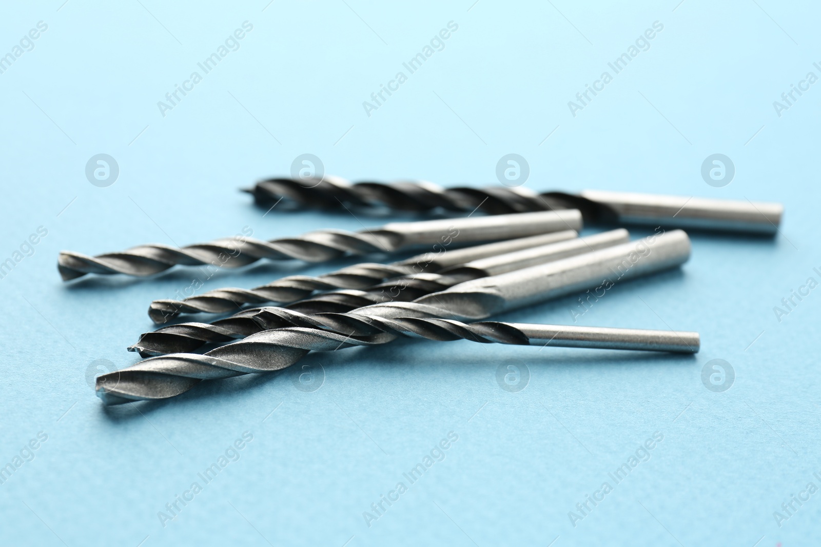 Photo of Many different drill bits on light blue background