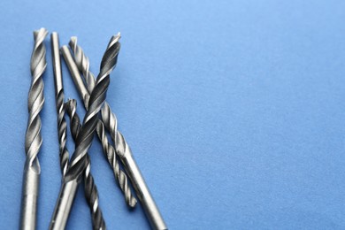 Photo of Many different drill bits on light blue background, space for text