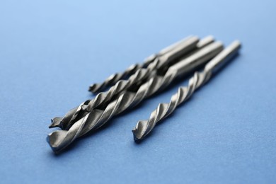 Photo of Many different drill bits on light blue background, closeup