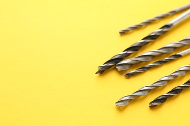 Photo of Many different drill bits on yellow background, space for text