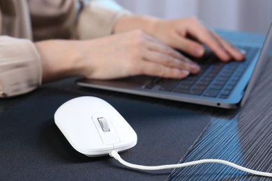 Photo of Woman working with laptop at black wooden table, focus on computer mouse