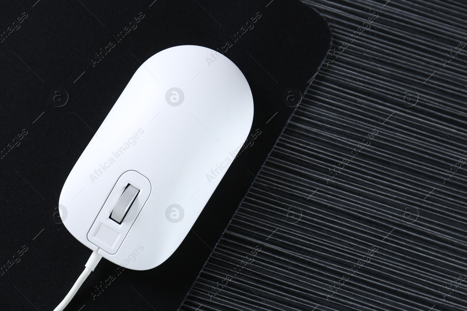 Photo of White computer mouse with mousepad on black wooden table, top view