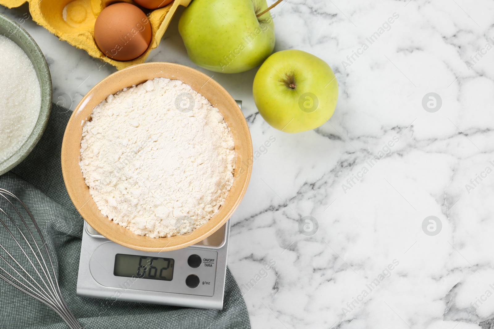 Photo of Flat lay composition of kitchen scale with bowl of flour and products on white marble table. Space for text